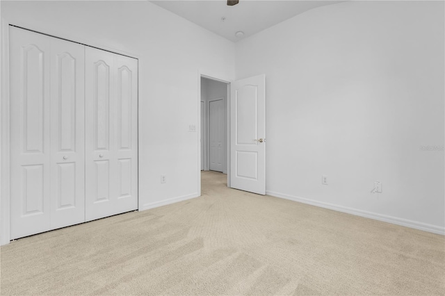 unfurnished bedroom featuring light colored carpet and a closet