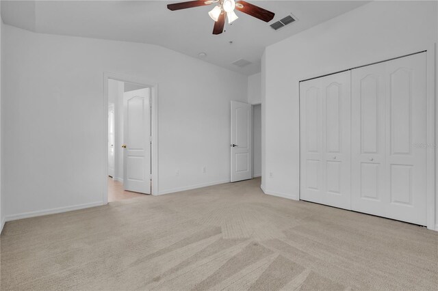 unfurnished bedroom with ceiling fan, a closet, light carpet, and vaulted ceiling