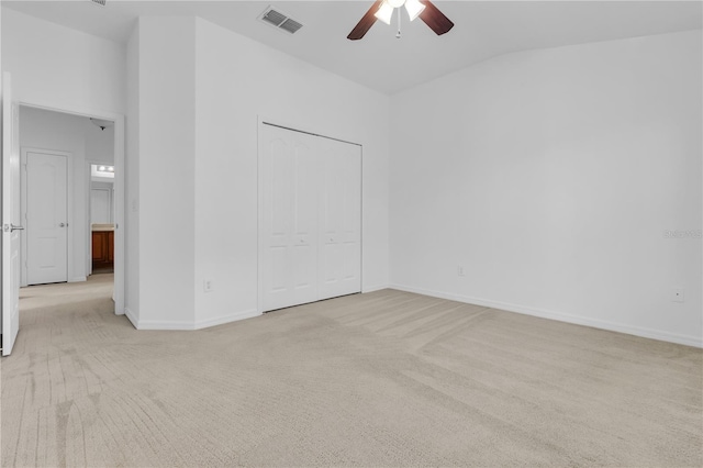 unfurnished bedroom with a closet, light colored carpet, vaulted ceiling, and ceiling fan