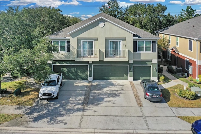 view of front of property featuring a garage, a balcony, and central AC