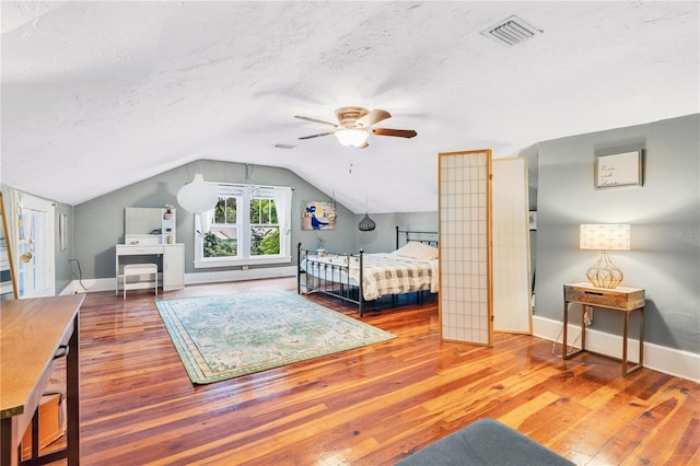 bedroom with hardwood / wood-style floors, a textured ceiling, vaulted ceiling, and ceiling fan