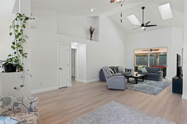 living room featuring a skylight, high vaulted ceiling, and light hardwood / wood-style floors