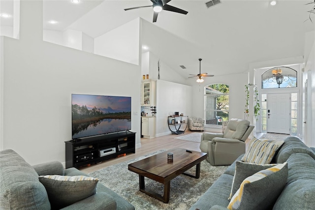 living room with an inviting chandelier, light hardwood / wood-style flooring, and high vaulted ceiling