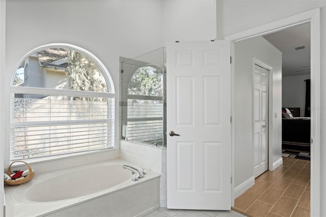 bathroom with separate shower and tub and plenty of natural light