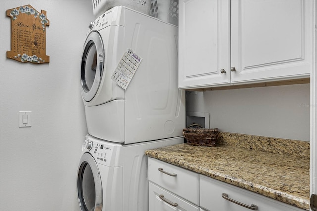 laundry area featuring cabinets and stacked washer and clothes dryer