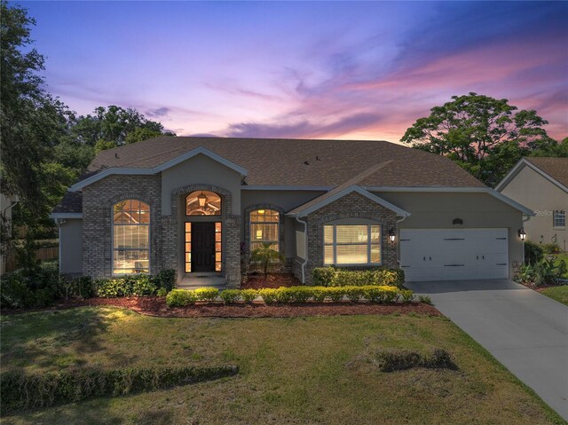 2226 Lake Marion Dr, Apopka, FL 32712 - ranch-style home with driveway, roof with shingles, a yard, an attached garage, and stone siding