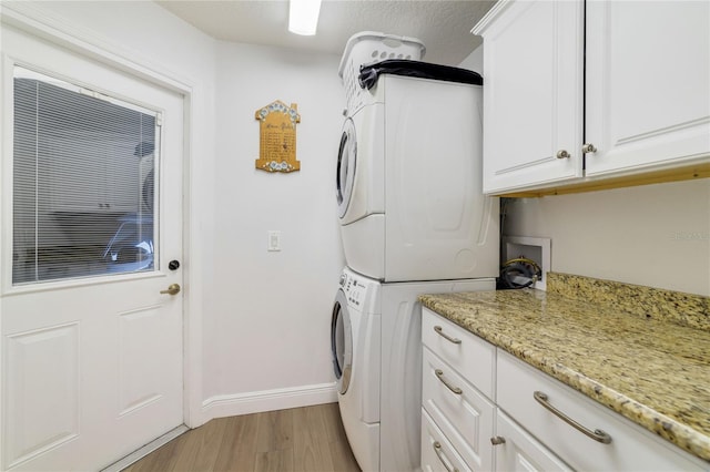 2226 Lake Marion Dr, Apopka, FL 32712 - laundry area with baseboards, stacked washer and clothes dryer, cabinet space, and light wood-style floors
