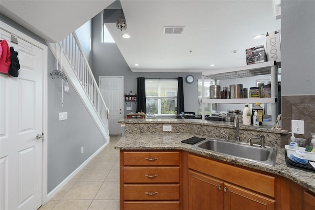 kitchen featuring light tile patterned floors, sink, stone counters, and vaulted ceiling