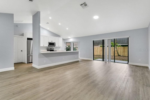 unfurnished living room with light wood-type flooring and high vaulted ceiling