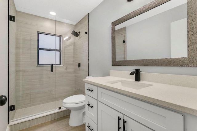 bathroom with vanity, toilet, wood-type flooring, and a shower with door