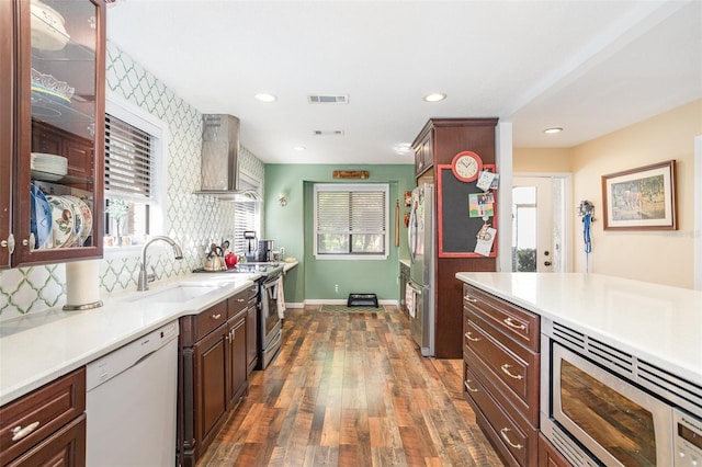 kitchen featuring sink, wall chimney exhaust hood, tasteful backsplash, dark hardwood / wood-style flooring, and appliances with stainless steel finishes