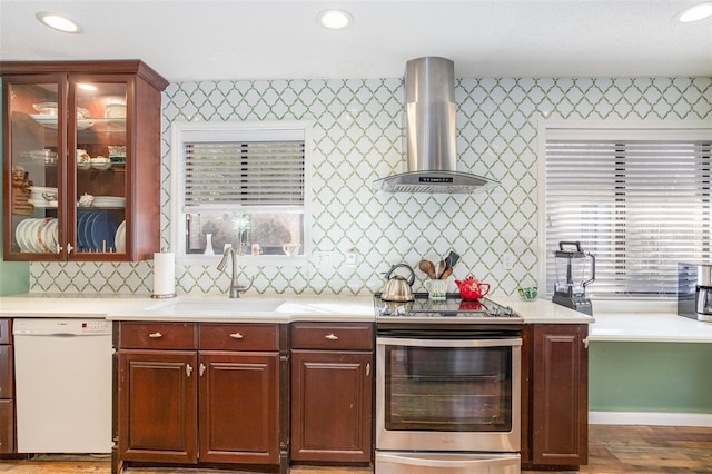 kitchen featuring dishwasher, wall chimney range hood, sink, electric stove, and hardwood / wood-style flooring