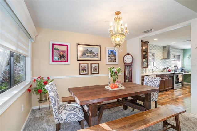 dining space with light carpet and a notable chandelier