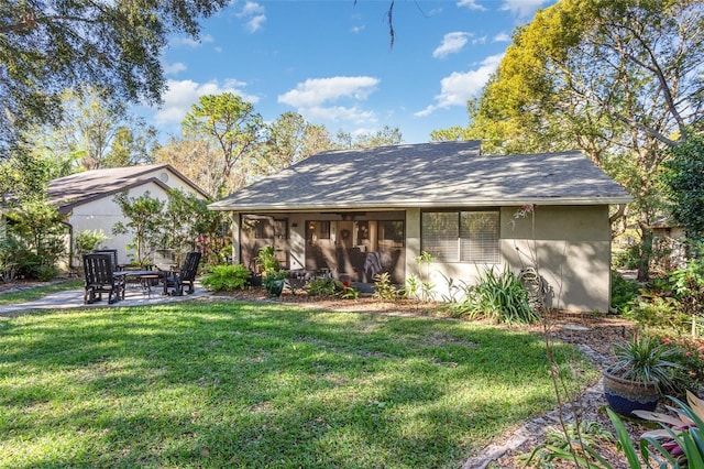 rear view of property featuring a sunroom, a patio, and a lawn