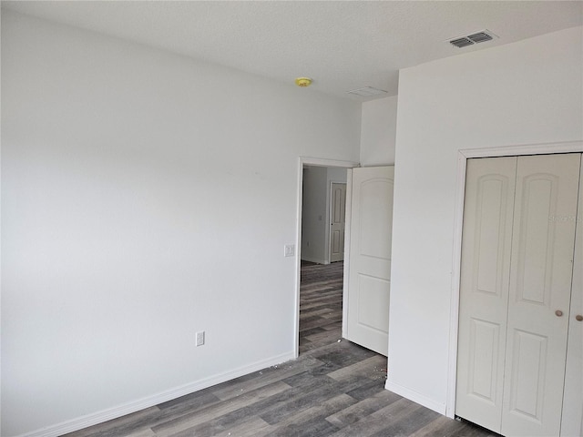 unfurnished bedroom featuring dark hardwood / wood-style flooring and a closet