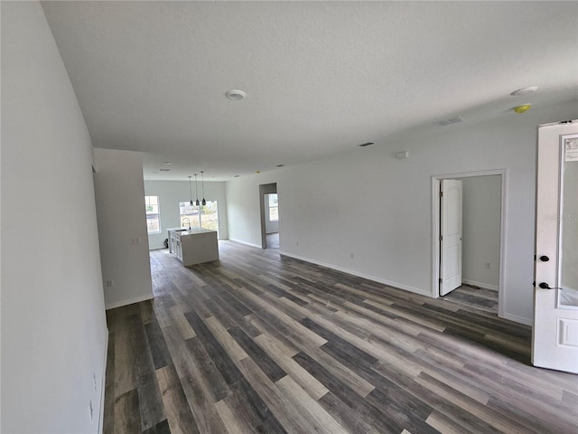 unfurnished living room with a textured ceiling and dark wood-type flooring