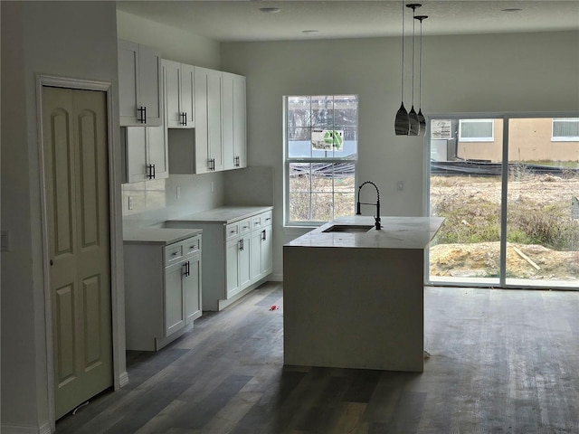 kitchen featuring plenty of natural light, sink, a center island with sink, white cabinetry, and hanging light fixtures