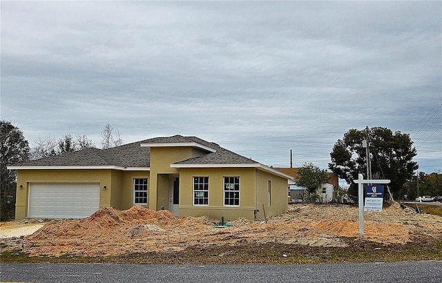 view of front of home featuring stucco siding, roof with shingles, and an attached garage