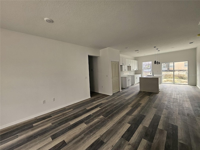 unfurnished living room with a textured ceiling, dark wood-type flooring, and sink