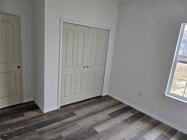 unfurnished bedroom featuring a closet and dark wood-type flooring