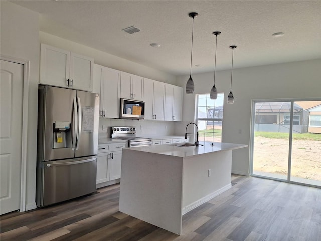 kitchen featuring visible vents, an island with sink, dark wood finished floors, white cabinetry, and appliances with stainless steel finishes