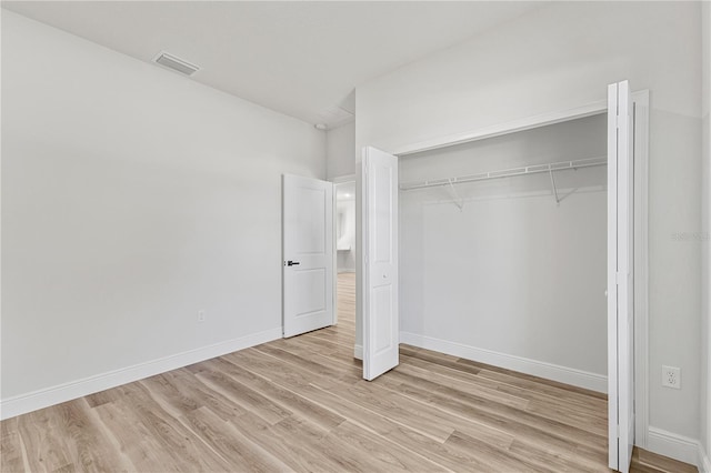 unfurnished bedroom with light wood-type flooring and a closet