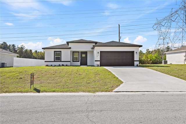 view of front of property with a front yard, central AC, and a garage