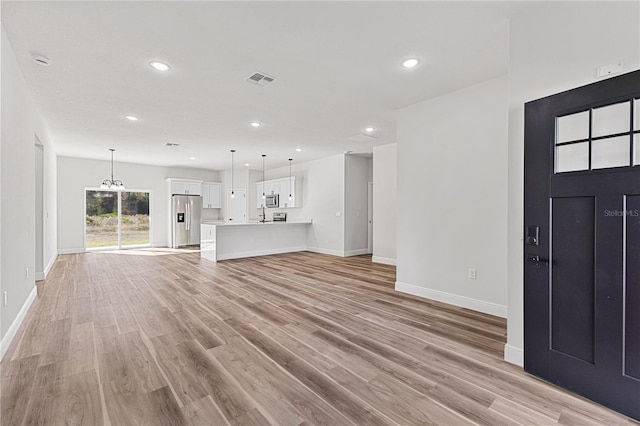 unfurnished living room with a chandelier and light hardwood / wood-style floors