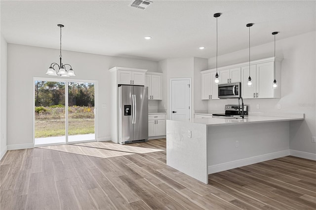 kitchen featuring kitchen peninsula, white cabinets, stainless steel appliances, and light wood-type flooring