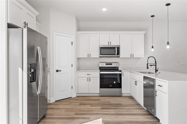 kitchen with pendant lighting, sink, light hardwood / wood-style flooring, white cabinetry, and stainless steel appliances