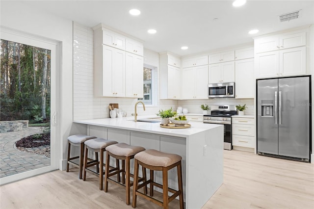 kitchen with sink, a breakfast bar area, white cabinetry, kitchen peninsula, and stainless steel appliances