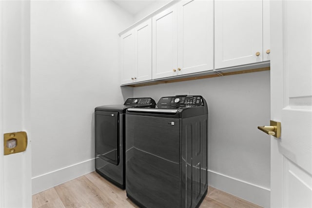 washroom with cabinets, washer and dryer, and light wood-type flooring