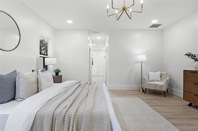 bedroom with an inviting chandelier, connected bathroom, and light hardwood / wood-style floors