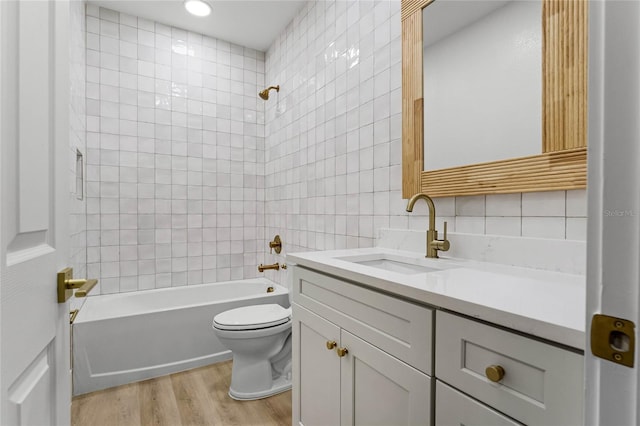 full bathroom with tile walls, hardwood / wood-style floors, toilet, and tiled shower / bath