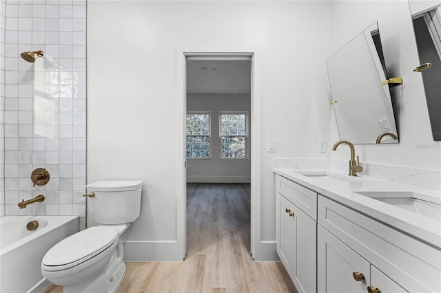 full bathroom with tiled shower / bath, vanity, toilet, and hardwood / wood-style floors