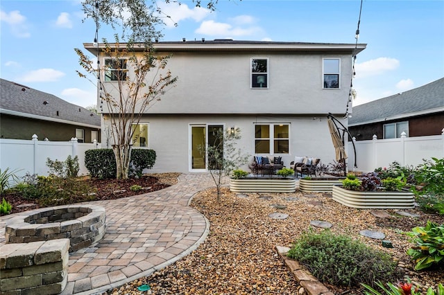 back of property with a fire pit and a patio area