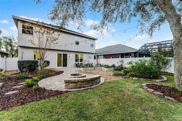 rear view of house with a fire pit, a lawn, a patio area, and glass enclosure