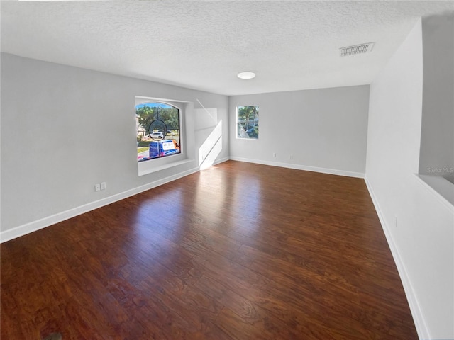 spare room with dark hardwood / wood-style floors and a textured ceiling