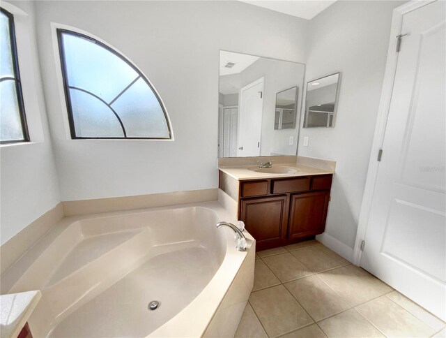 bathroom with tile patterned floors, tiled bath, plenty of natural light, and vanity