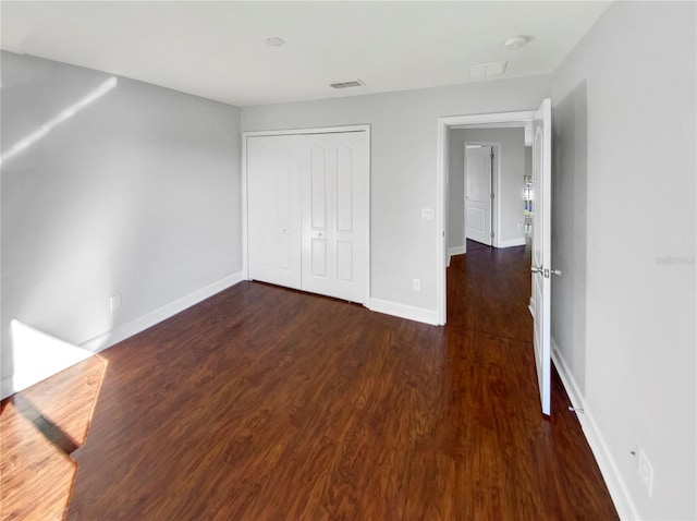 unfurnished bedroom featuring dark wood-type flooring and a closet