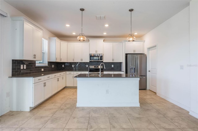 kitchen with white cabinetry, a kitchen island with sink, pendant lighting, and stainless steel appliances