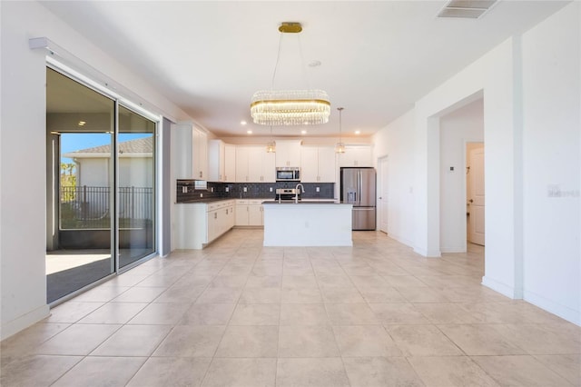 kitchen featuring hanging light fixtures, an island with sink, a notable chandelier, white cabinetry, and stainless steel appliances