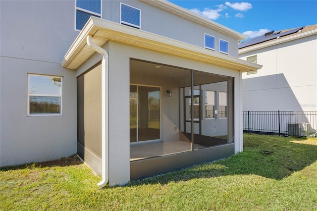 back of property featuring a sunroom, a lawn, and central AC