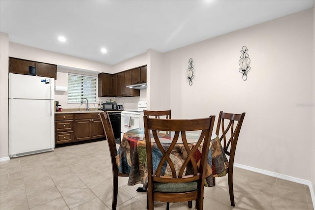 kitchen featuring black appliances, dark brown cabinetry, sink, and light tile patterned floors