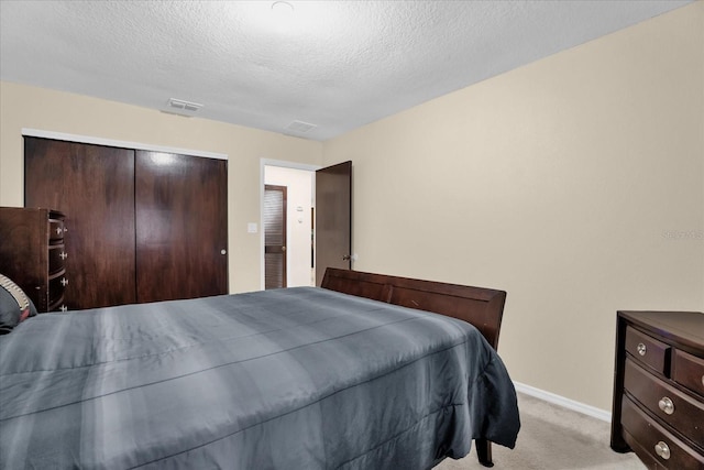 carpeted bedroom with a closet and a textured ceiling