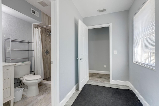 bathroom featuring hardwood / wood-style floors, vanity, toilet, and walk in shower