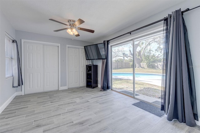 unfurnished living room with ceiling fan, light hardwood / wood-style floors, and a textured ceiling