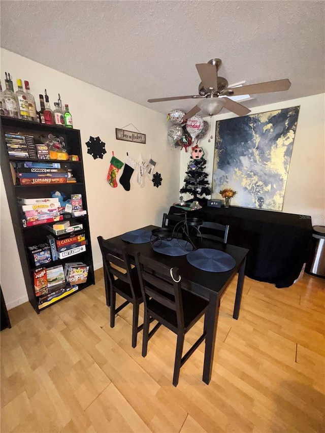 dining area featuring hardwood / wood-style flooring, ceiling fan, and a textured ceiling