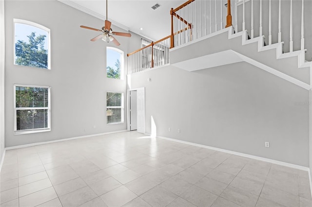 unfurnished living room featuring a high ceiling, light tile patterned floors, ceiling fan, and a healthy amount of sunlight