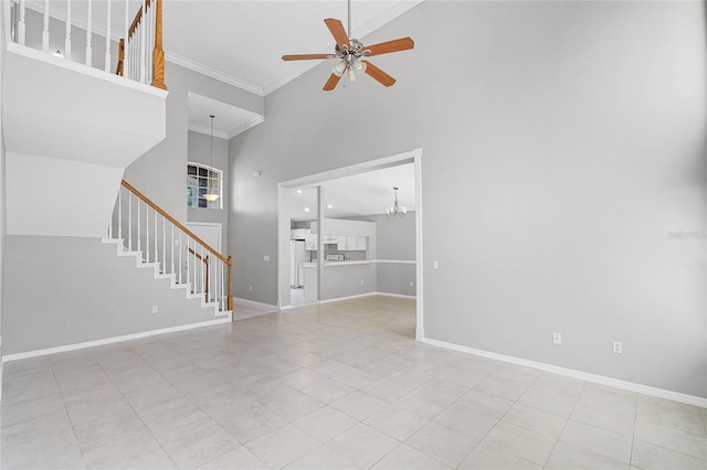 unfurnished living room with a towering ceiling, ceiling fan with notable chandelier, and ornamental molding